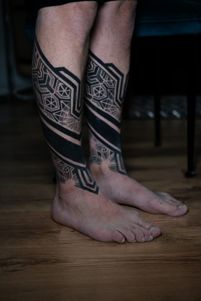 Geometric symmetrical leg tattoo covering both legs. 